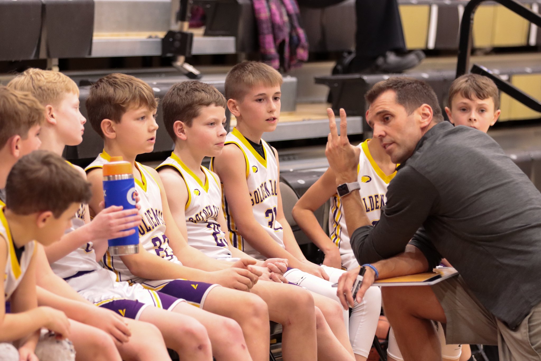 Junior Golden Eagles basketball coach giving instructions to young players during practice