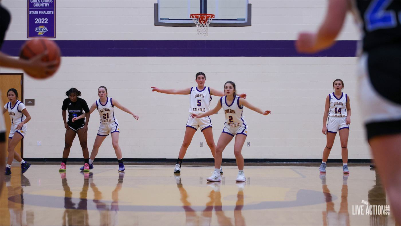 Junior Golden Eagles girls' basketball team in white and purple uniforms on the court