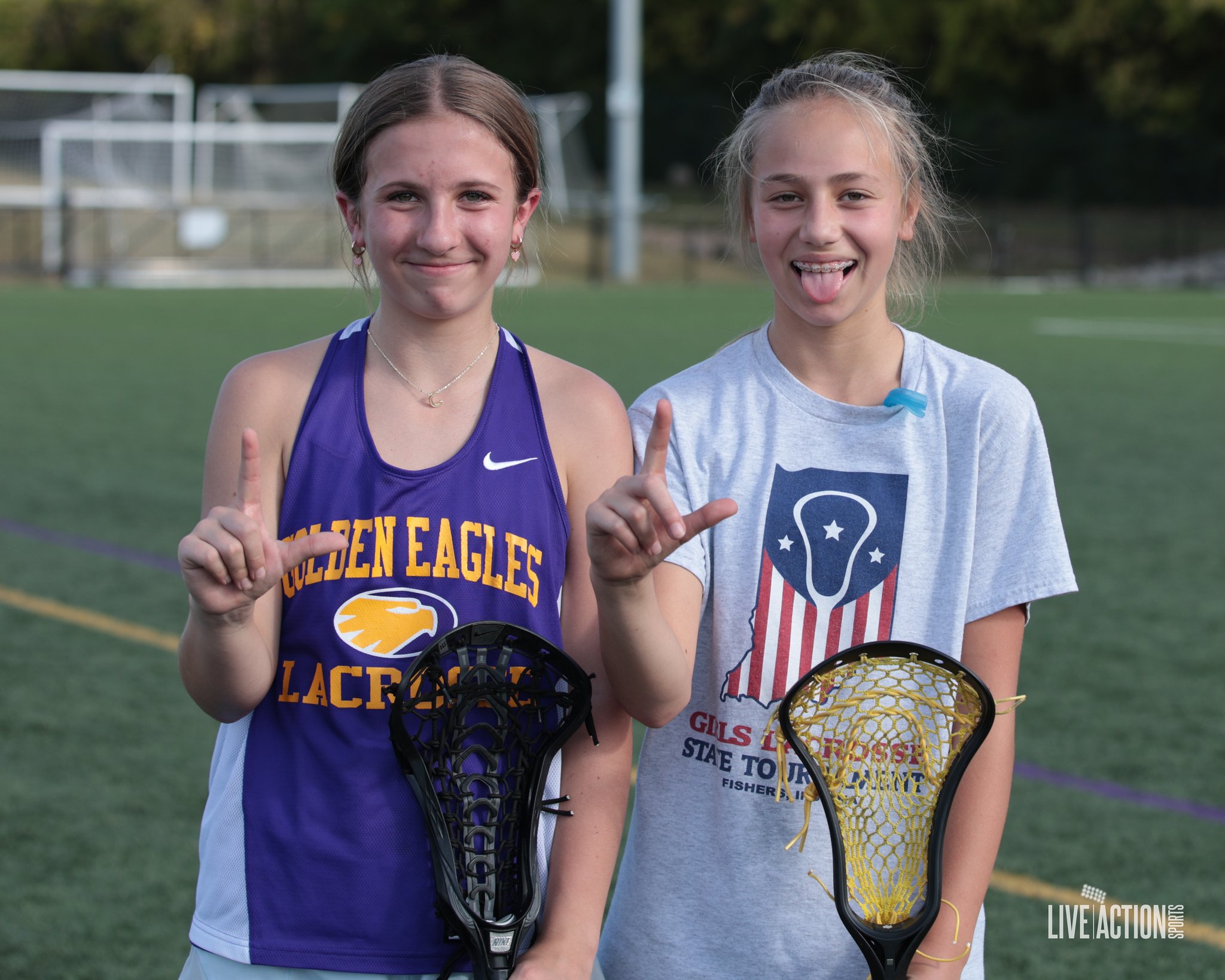 Junior Golden Eagles girls standing on a sports field holding lacrosse sticks